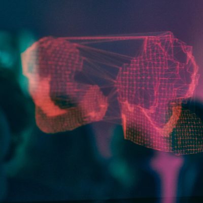 A digital visualisation of abstract, red 3D shapes connected by lines floats against a blurred, dark blue and purple background, suggesting technology or data networks.