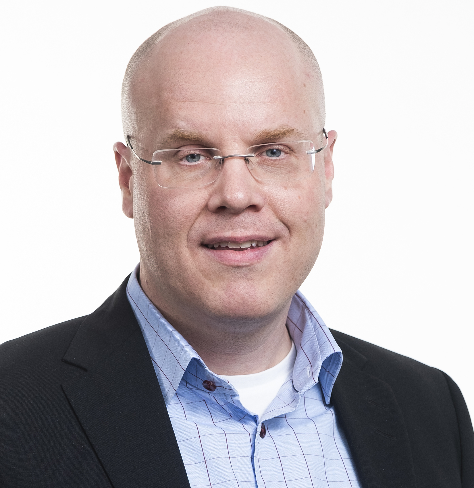 A bald man wearing glasses, a light blue checked shirt, and a dark blazer, smiling slightly against a plain white background—radiating confidence and openness to partnership.