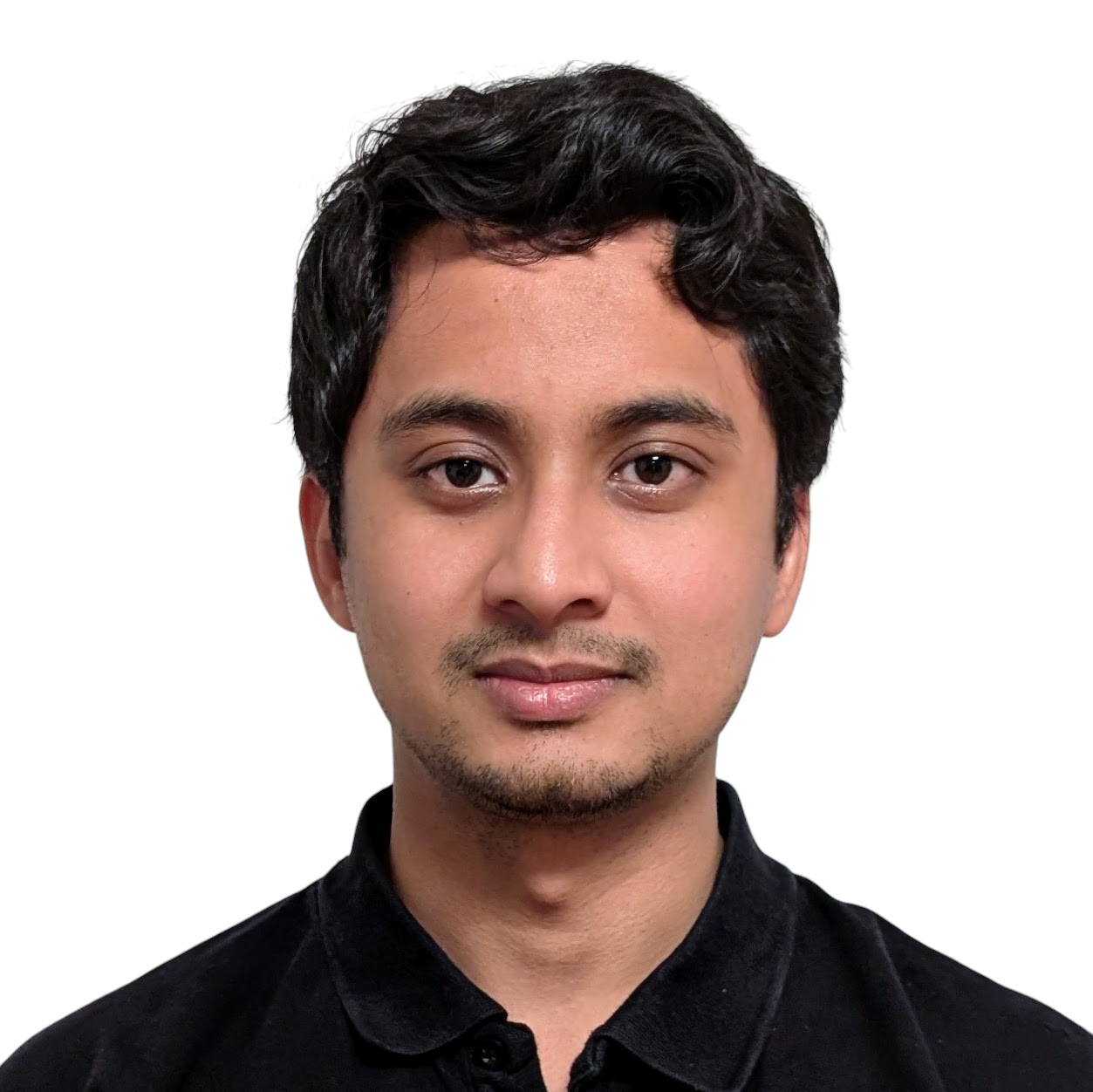 A young man with short, wavy black hair and light facial hair, wearing a black collared shirt, looks directly at the camera against a plain white background.
