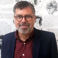 A middle-aged man with glasses, short hair, and a beard, wearing a dark blazer over a red shirt, smiles in front of a black-and-white illustrated background.