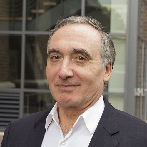A middle-aged man in a dark blazer and white collared shirt.